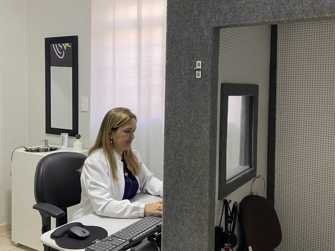 Profissional realizando exame de audiometria na cabine acústica da Atual Medicina